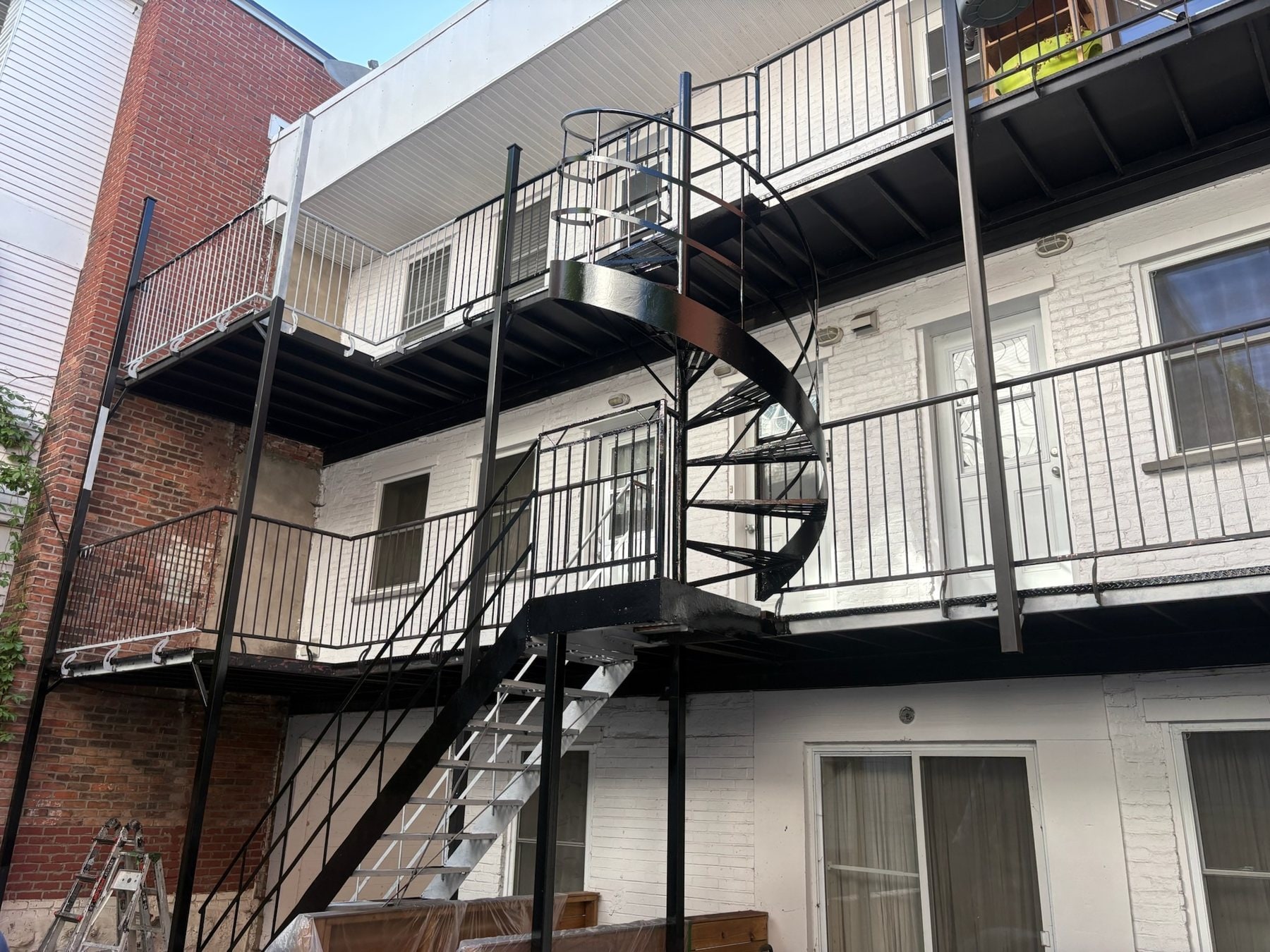 Balcons et escalier en colimaçon en fer forgé noirs sur trois niveaux