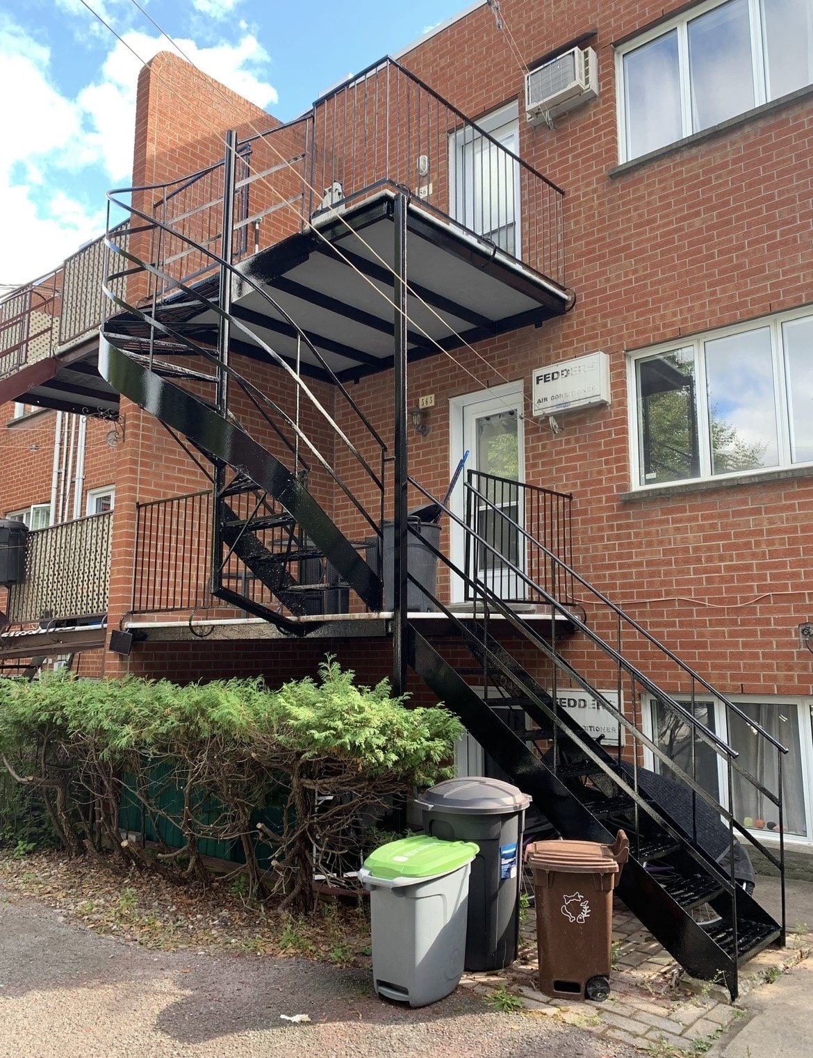 Balcons et escaliers en fer forgé noirs sur un immeuble de brique rouge