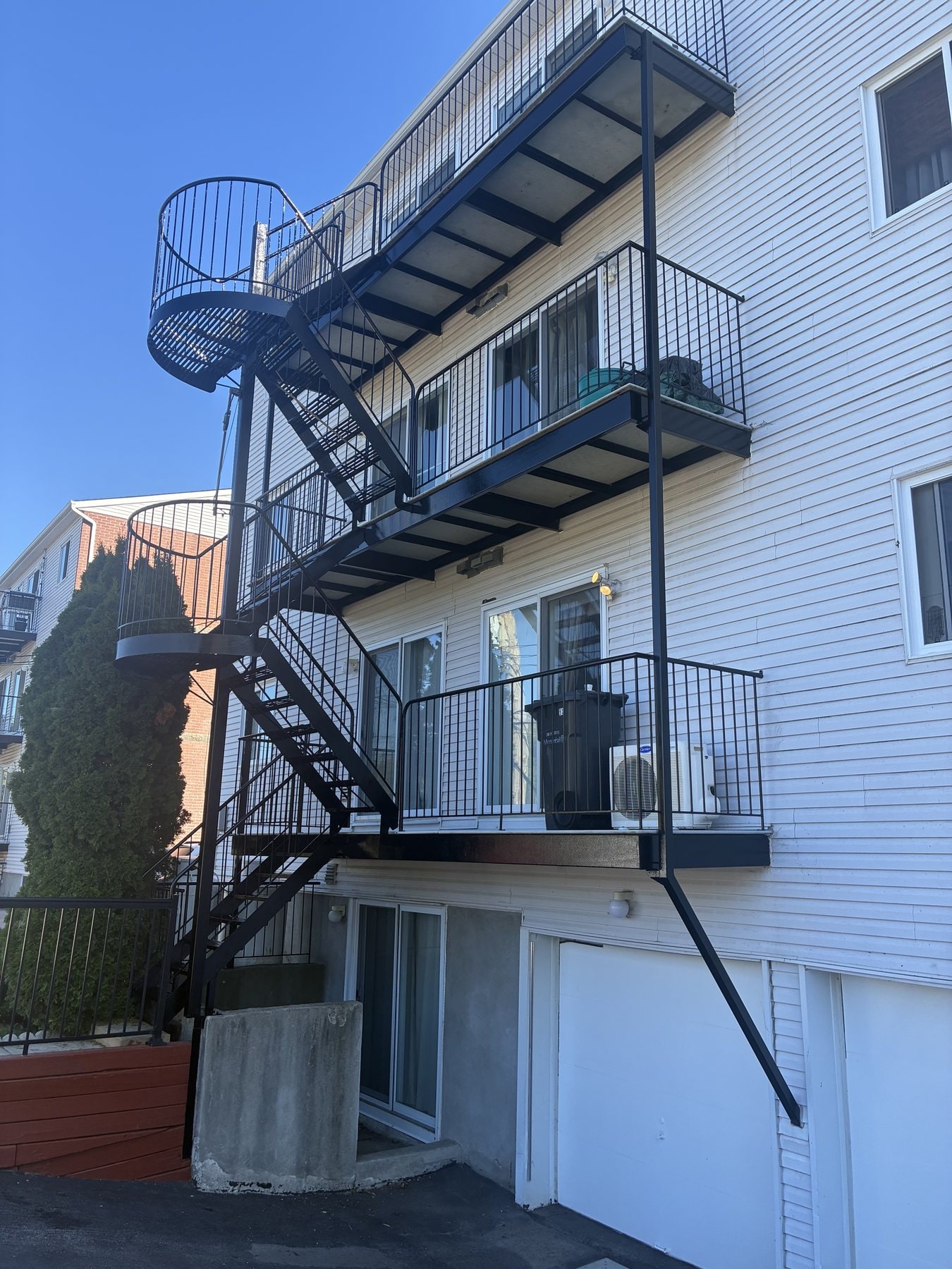 Balcons et escaliers en fer forgé noirs sur trois niveaux, revêtement blanc