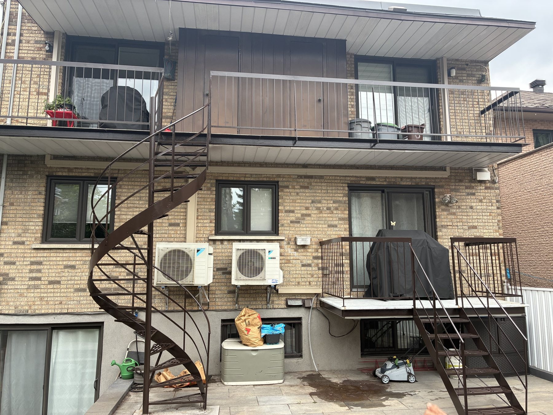 Escalier en colimaçon et balcons en fer forgé sur une façade de brique beige