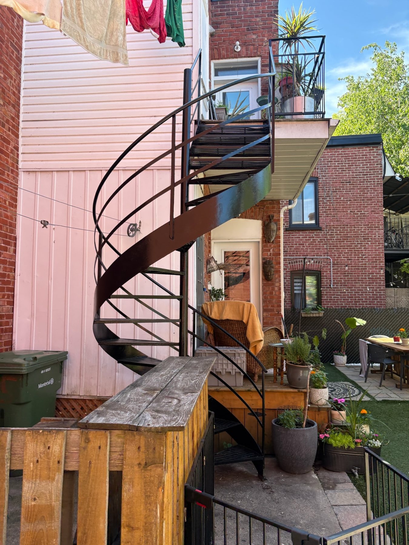 Escalier en colimaçon en fer forgé dans une cour fleurie