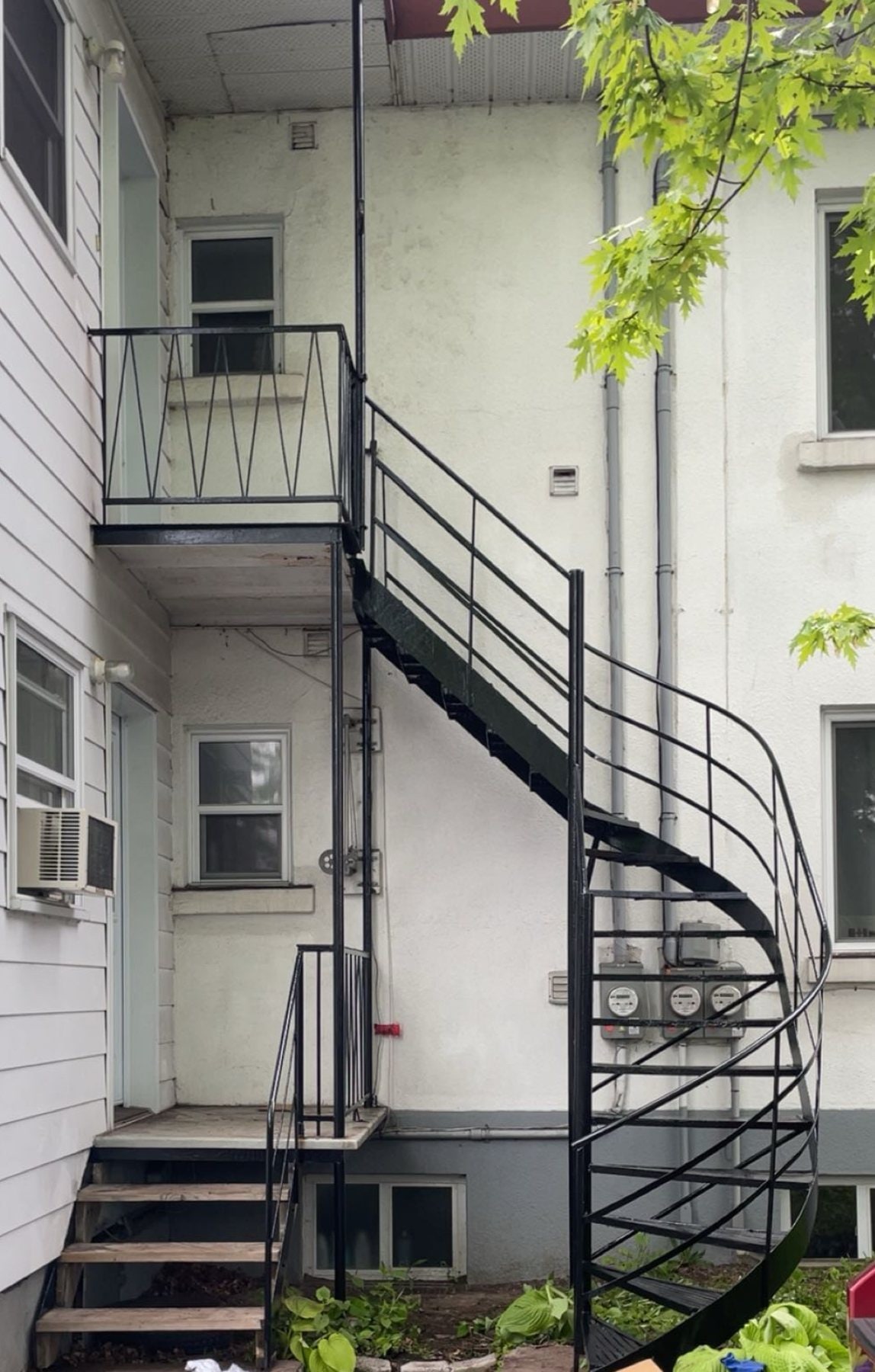 Escalier en colimaçon en fer forgé noir contre un mur blanc