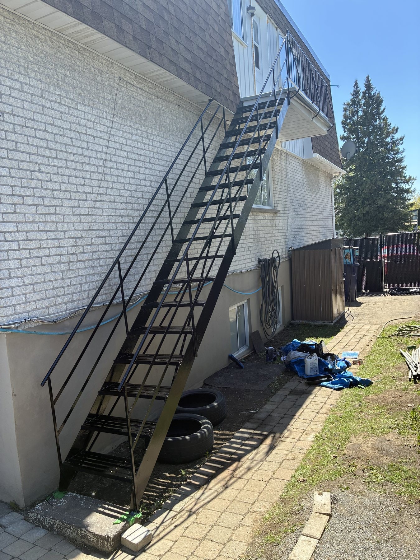 Escalier droit en fer forgé noir sur un mur de brique blanche