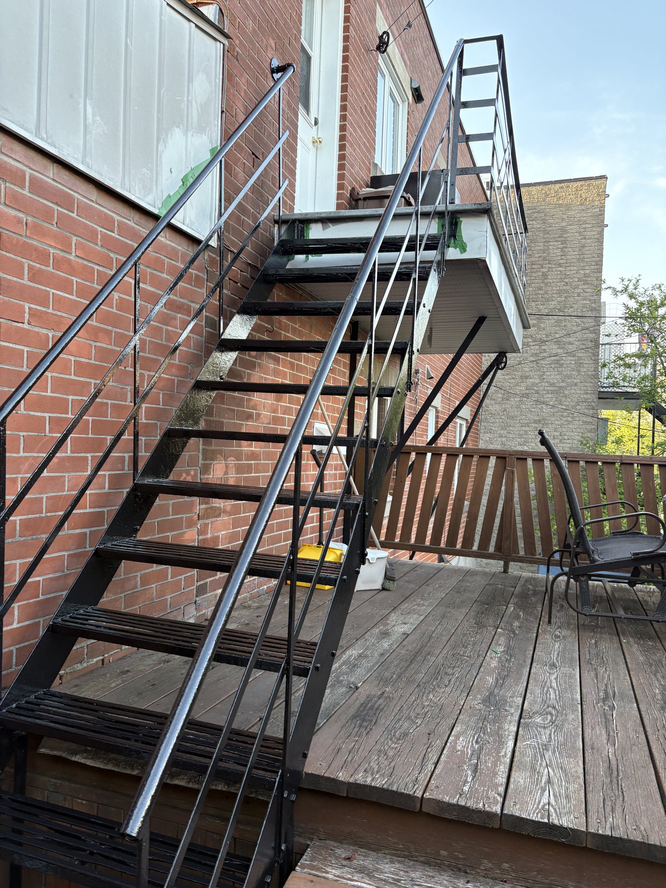 Escalier droit en fer forgé noir descendant sur une terrasse en bois