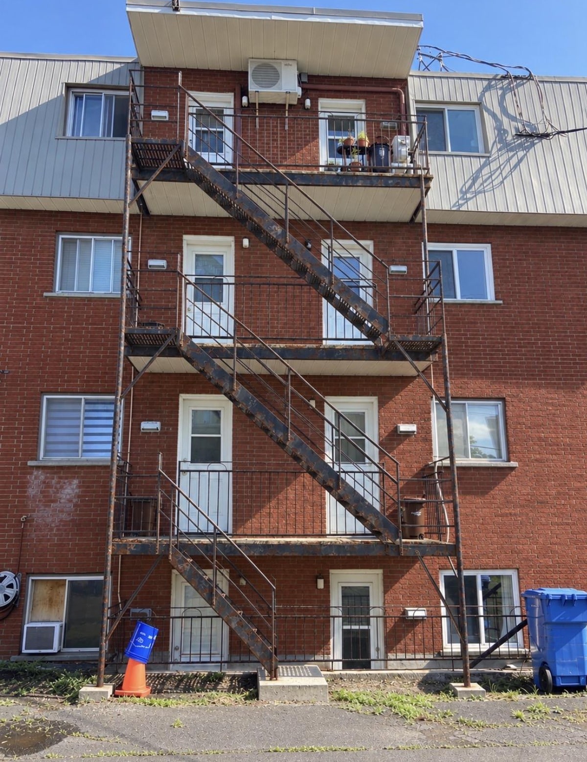 Escalier de secours de trois étages sur un immeuble de brique rouge, avant les travaux