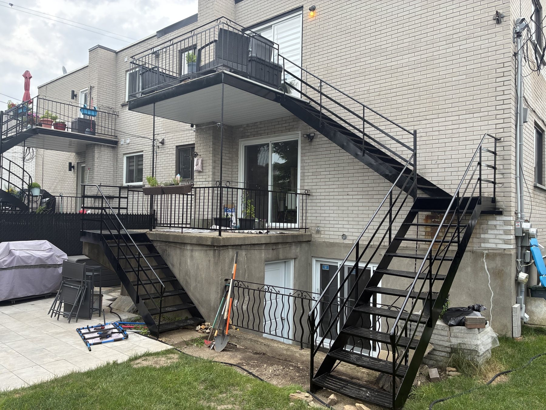 Escaliers et balcons en fer forgé noirs donnant sur une cour gazonnée