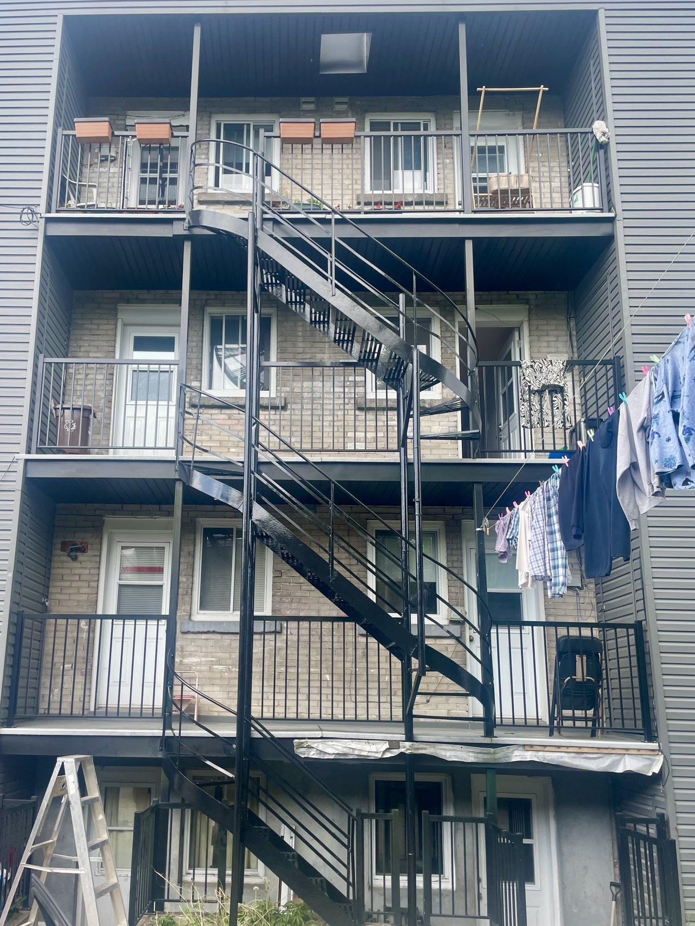 Escaliers de secours et balcons en fer forgé repeints sur un immeuble de quatre étages