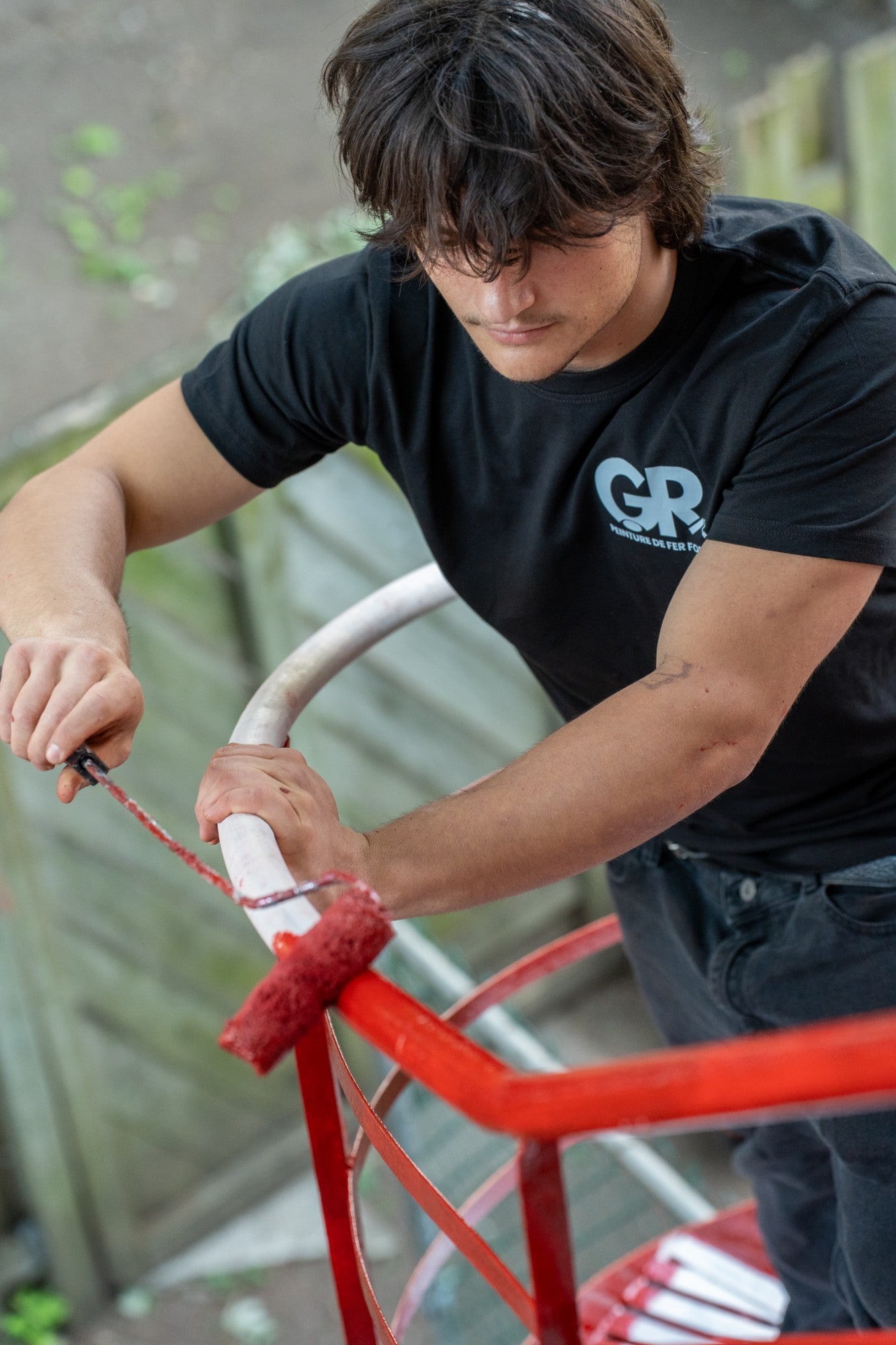 Peintre de Peinture GR qui applique l'apprêt rouge au rouleau