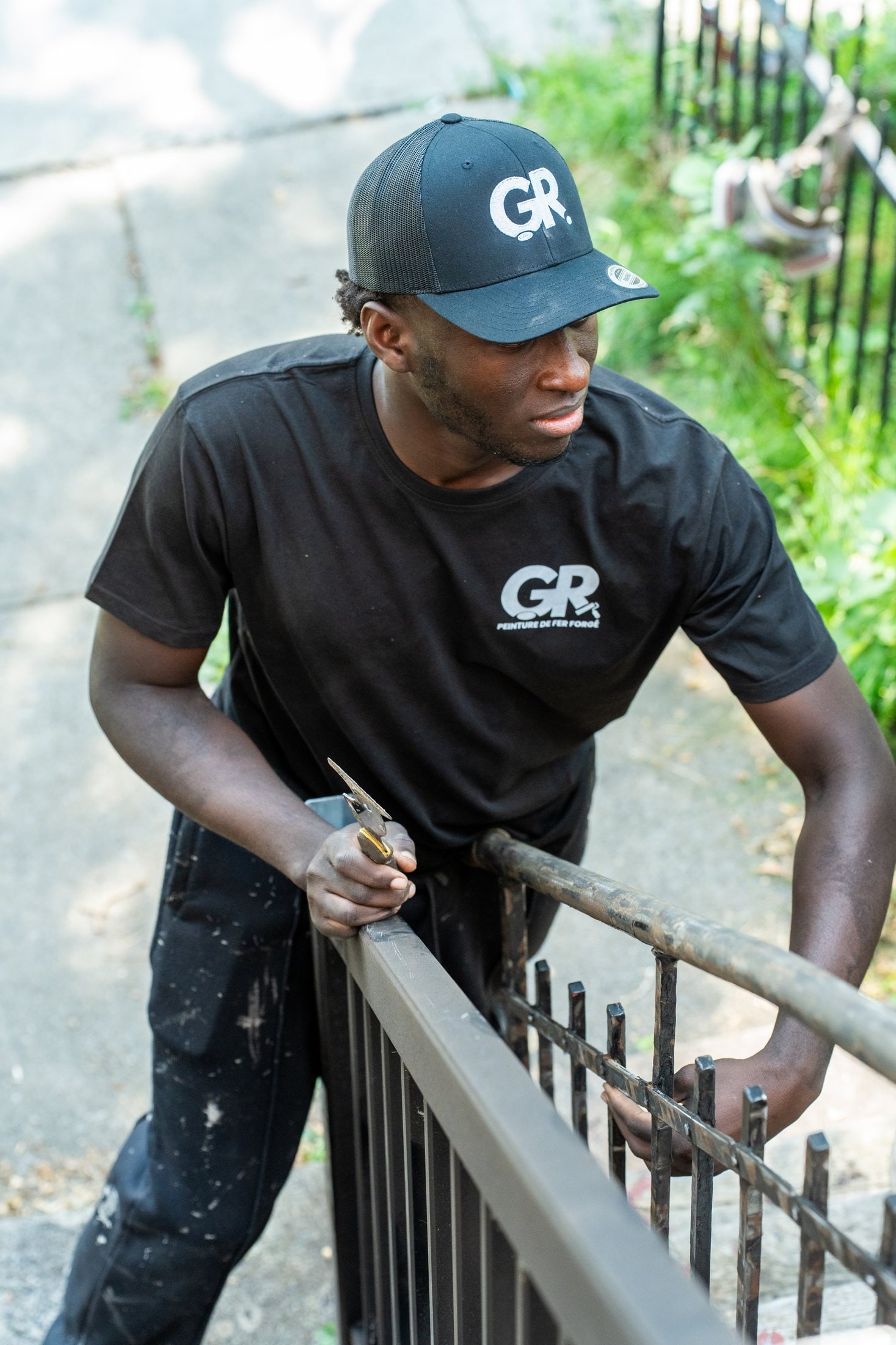 Peintre en casquette Peinture GR qui gratte une rampe
